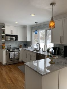 a kitchen with white cabinets and stainless steel appliances in the middle of an open floor plan