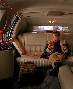 a young boy sitting in the back of a car eating pizza