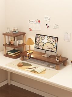 a desk with a computer, lamp and other items on top of it in front of a white wall