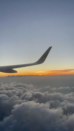 an airplane wing above the clouds at sunset