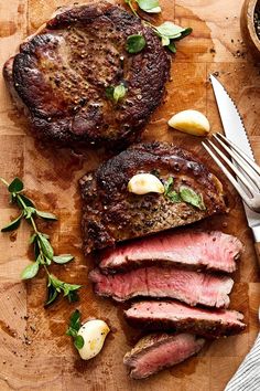 some meat is on a cutting board next to a knife and fork