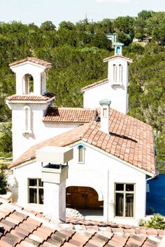 an aerial view of a white church with red tile roof and steeple overlooking the water