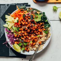 a white plate topped with rice, carrots and lettuce next to a cutting board