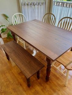 a wooden table with two chairs and a bench in front of it on a hard wood floor