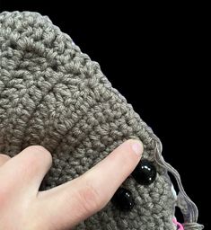 a hand is holding onto a crocheted object