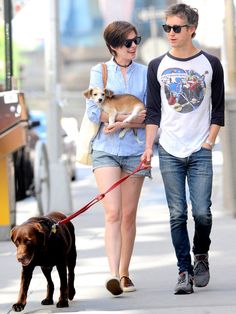 a man and woman walking their dog down the street