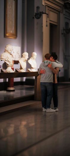 two people hugging each other in front of some statues