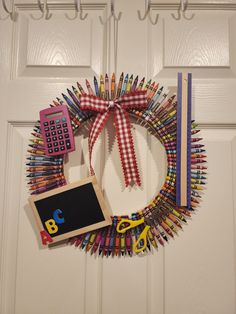 a wreath made out of crayons and colored pencils is hanging on the front door