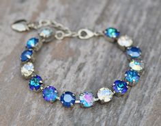 A gorgeous new bracelet made with Swarovski crystal. The bracelet features 8mm crystals ranging in color from royal blue de lite, royal blue, aqua transmission, crystal moonlight, and bermuda blue color. Crystals are hand set into a premium bracelet setting, and prong set. Bracelet will adjust to fit wrist sizes 6 inches and up. Please choose desired metal finish at checkout. Shown in silver in images above. ** Nickel and lead free Adjustable Blue Bracelets With Sparkling Stones, Blue Crystal Bracelet With Sparkling Stones, Blue Crystal Bracelet With Rhinestones, Adjustable Blue Crystal Rhinestone Bracelet, Adjustable Blue Crystal Bracelet With Rhinestones, Blue Crystal Bracelet, Set Bracelet, Stacked Necklaces, Crystal Bracelet