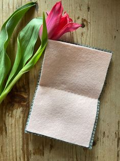 a pink tulip sitting on top of a wooden table next to a piece of cloth