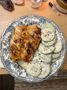 a plate with chicken, cucumbers and sauce on it