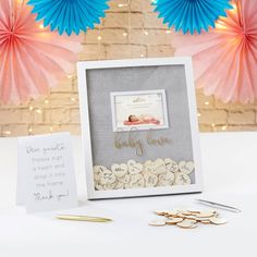 there is a picture frame and some paper fans next to it with a baby's name on it