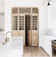 a kitchen with white cabinets and wooden doors