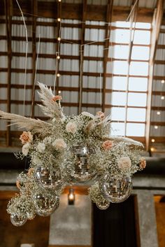 a chandelier with flowers and feathers hanging from it's centerpieces