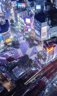 an aerial view of a city at night with lots of lights and people on the street