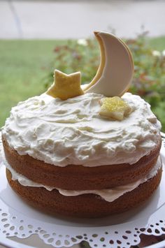 a cake with icing and stars on top sitting on a plate outside in the sun