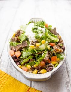 a white bowl filled with salad on top of a wooden table