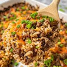 a spoon full of rice and ground beef in a casserole dish with green onions