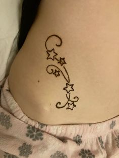 a woman's lower back tattoo with stars and swirls on her side belly