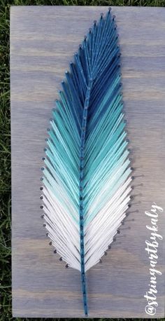 a blue and white feather sitting on top of a wooden board