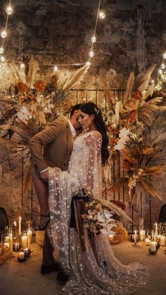 a bride and groom are kissing in front of an artistic backdrop with candles on the floor