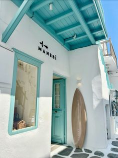 a white building with a surfboard on the outside and blue trim around the door