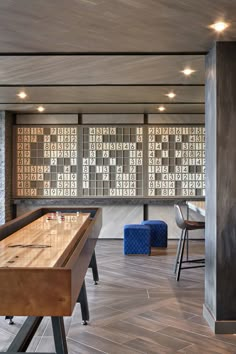 an indoor game room with wood flooring and large tiles on the wall behind it