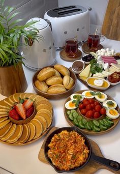 a table topped with plates of food and bowls of fruit next to an air fryer