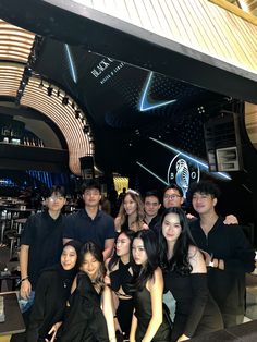 a group of people standing next to each other in front of a bar with neon lights