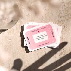 three playing cards sitting on top of each other next to a glass cup and saucer