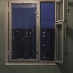 an open window with the night sky seen through it's panes in front of a cityscape