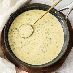 a bowl of soup with a spoon in it on a wooden plate next to a napkin