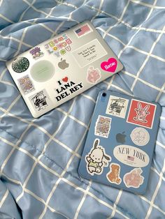 an ipad case sitting on top of a bed covered in stickers