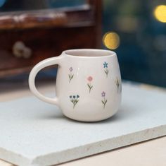 a white coffee cup with flowers painted on it