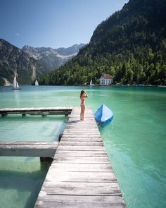 a small child standing on a dock next to a body of water with boats in it