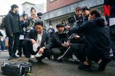 a group of people sitting on the side of a road next to each other with cameras around them