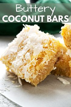 two pieces of coconut bar sitting on top of a piece of parchment paper with the words buttery coconut bars