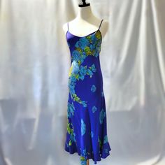 Rare Vintage Purple Betsey Johnson Sundress From The 1990's. Dress Features A Ruffled Hem And A Diagonal Floral Pattern To Create A Figure Flattering Silhouette. The Dress Has Criss-Crossed Adjustable Straps In The Back To Allow The Wearer To Fit The Dress To Their Body. A Perfect Dress For Summer. The Dress Is In Very Good Condition With Some Signs Of Wear At The Lower Front (Below The Knees - Only Visible If Scrutinized In Bright Sunlight) And A Difficult To Read Fabric Tag. It Appears To Say Purple Fitted Slip Dress, Fitted Purple Slip Dress, Purple Silk Bias Cut Dress, Purple Fitted Maxi Sundress, Blue Summer Dresses With Bias Cut, Summer Blue Bias Cut Dress, Fitted Bias Cut Beach Dress, Purple Silk Maxi Dress For Summer, Purple Silk Floral Print Maxi Dress