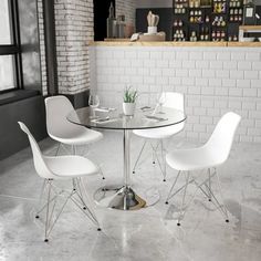 a glass table with four white chairs in front of a brick wall and flooring