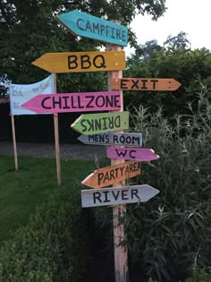 a wooden pole with many different colored signs on it's sides and trees in the background