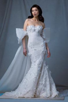 a woman in a white wedding dress standing on a blue and white background with her arms outstretched