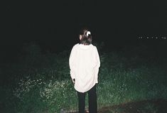 a person standing in the grass at night with their back turned to the camera,