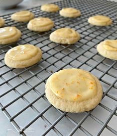 cookies cooling on a wire rack with frosting and orange sprinkles in the background