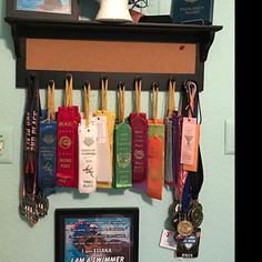 there are many medals hanging on the wall next to a framed photo and an award plaque