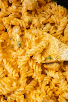 macaroni and cheese being stirred with a wooden spoon