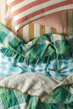 an unmade bed with green and blue plaid sheets