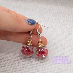 These snow globe earrings are the perfect holiday touch to any outfit! The plastic globes are filled with a bunch of star shaped sequins! They're lightweight and catch the light. All of our hooks are silver-plated, but we also do 925 sterling silver hooks, clip-ons, and clasp hooks for stretched ears for free on request. All you need to do is leave a note when checking out. Be sure to check out our store for more quirky jewellery and fun earrings: https://www.etsy.com/uk/shop/CandyGoblins Star-shaped Party Earrings With Ear Wire, Star Shaped Earrings With Ear Wire For Party, Pink Star Earrings For Party, Pink Star-shaped Party Earrings, Star Shaped Glitter Earrings For Party, Red Star Charm Earrings For Gift, Christmas Star-shaped Jewelry For Parties, Red Glitter Party Earrings, Red Glitter Earrings For Party