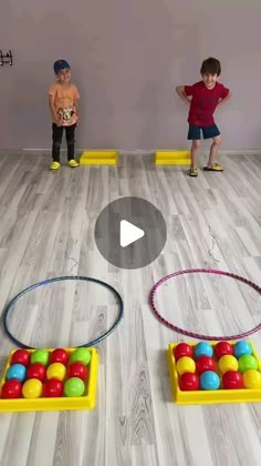 two children are playing with colorful balls on the floor