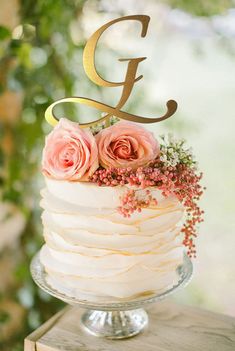 a white cake with pink flowers and the letter g on top