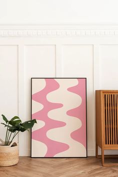 a pink and white abstract art piece next to a wooden chair with a potted plant